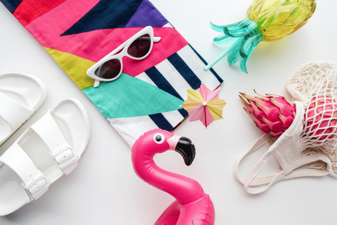 Flat lay of several types of the best summer promotional products including a beach towel, flamingo pool toy, and pineapple water bottle