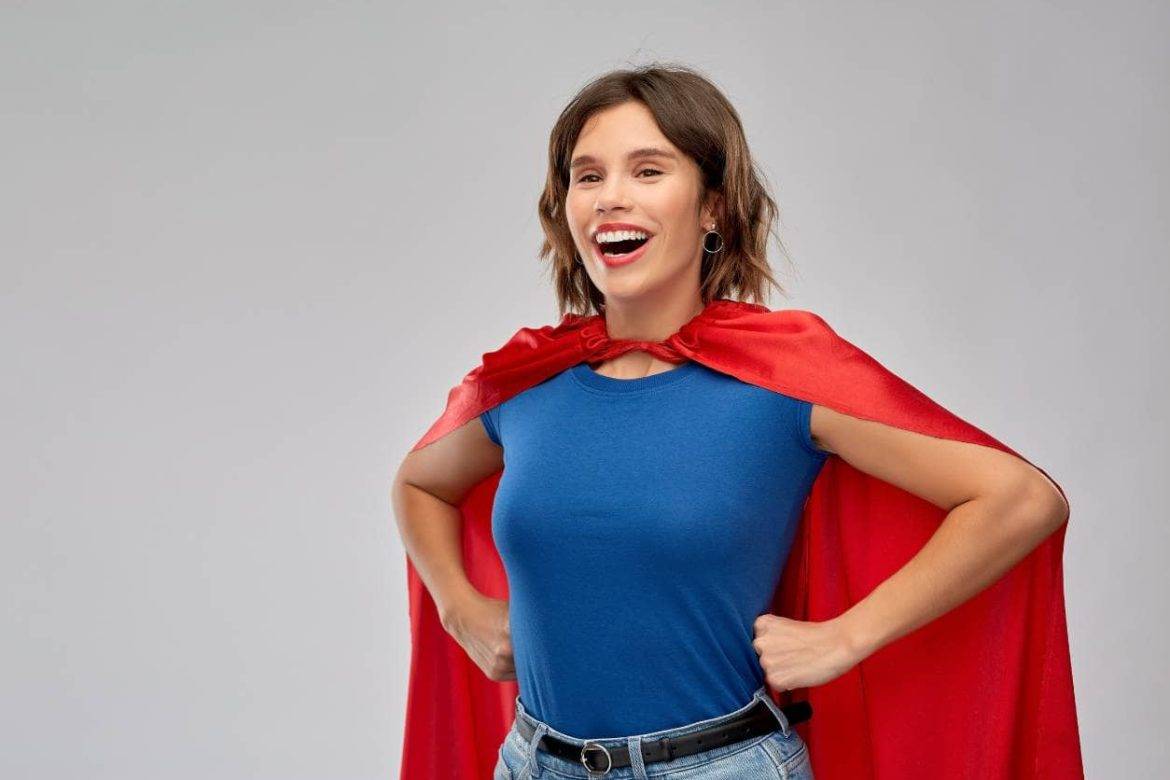 Woman with hands on hips wearing blue shirt and red cape, representing proactive customer service