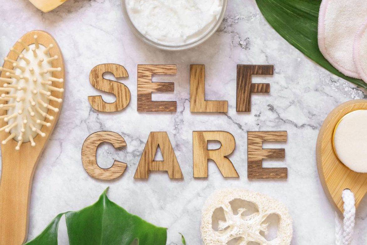 SELF CARE in wooden letters surrounded by self-care items