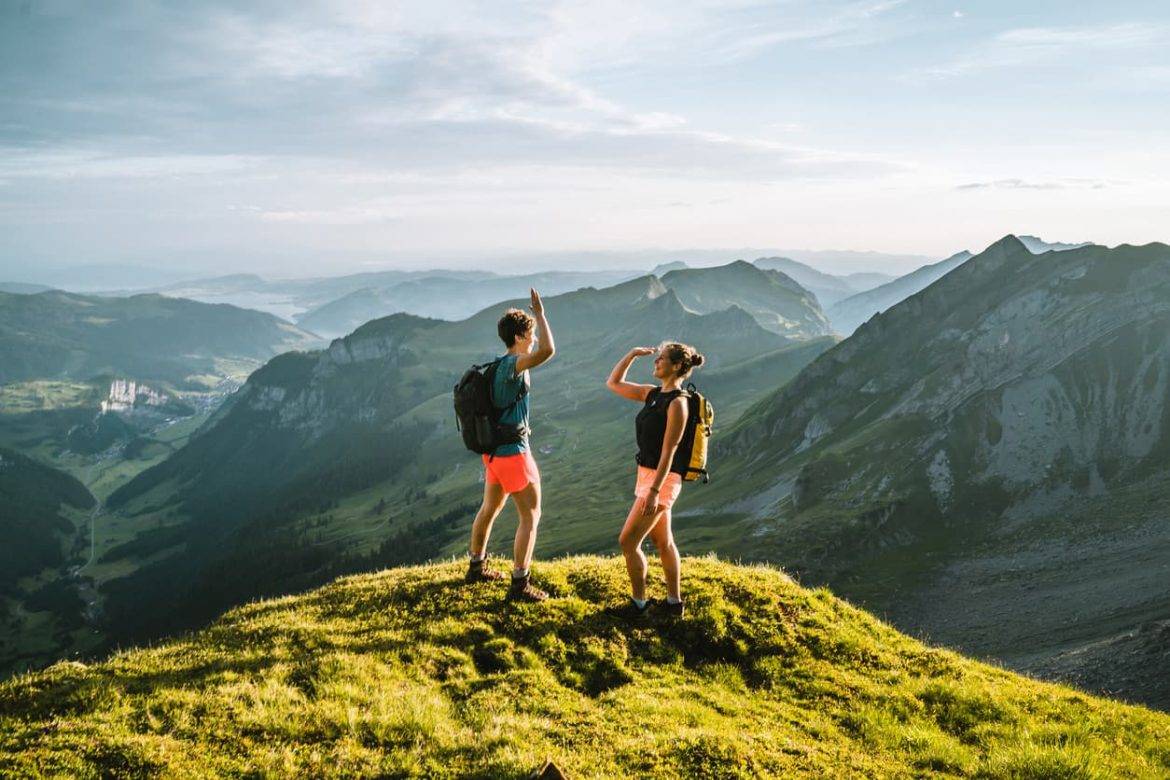 A man and women high fiving at the top of a mountain