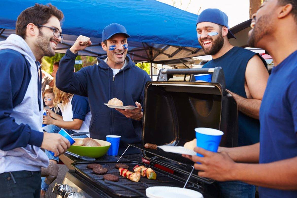 Group Of Male Sports Fans Tailgating In Stadium Car Park